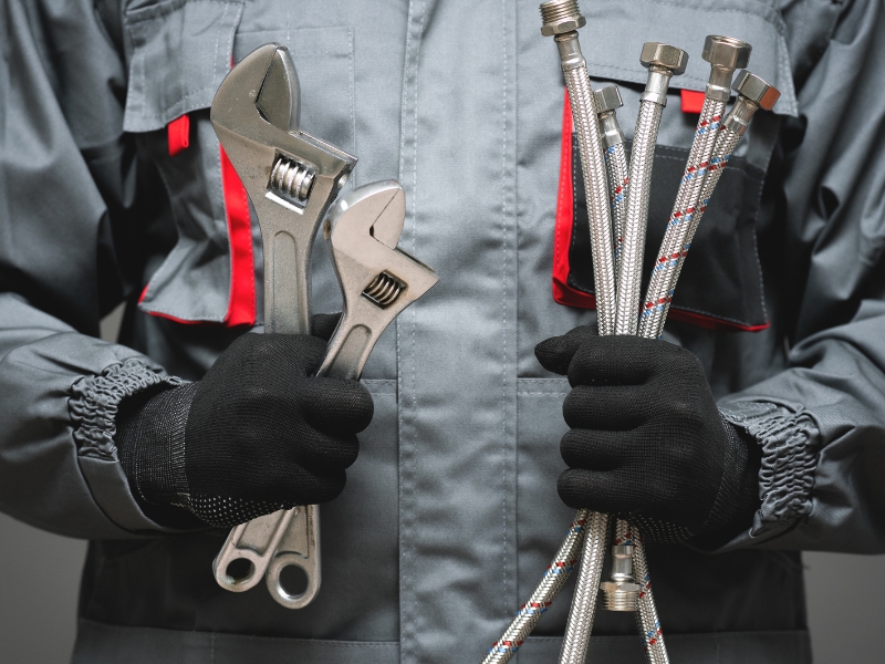 Klucze nastawne w pracy hydraulika – narzędzia nie do zastąpienia zwykłymi kluczami Hydraulik trzymający klucze nastawne i węże elastyczne do instalacji wodnej